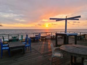 a wooden deck with tables and chairs on the beach at BEAUSÉJOUR Plage in Kribi