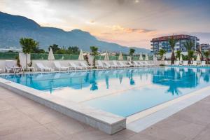a large swimming pool with white chairs and a building at Graf Victor Hotel - All Inclusive Non Alcoholic Drinks in Çamyolu