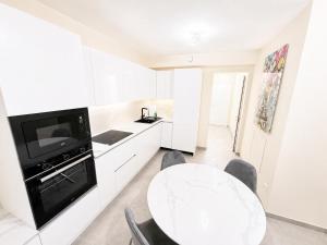 a white kitchen with a white table and a tv at The Eight in Luxembourg