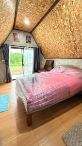 a bedroom with a bed and a large window at บ้านสวนแม่จันทร์เพ็ญ in Chiang Dao