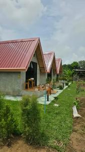 a house with a red roof and a yard at บ้านสวนแม่จันทร์เพ็ญ in Chiang Dao