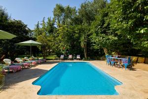 a blue swimming pool with chairs and tables and umbrellas at Can Portell by 123ole, B&B - Casa Rural in Sant Andreu del Terri +32 photos