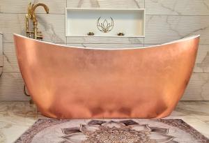 a copper bath tub in a bathroom with a picture at Coastal Harmony B&B in Portstewart +15 photos