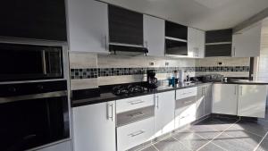 a kitchen with white cabinets and black appliances at Pent House La Castellana in Armenia