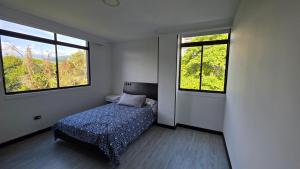 a bedroom with a bed and two windows at Pent House La Castellana in Armenia