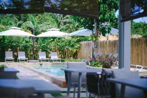 a pool with tables and chairs and umbrellas at Namal Resort - Free scooter and Gym access in El Nido