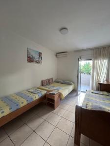 a room with two beds in it with a window at Apartmani Miladinović in Sutomore