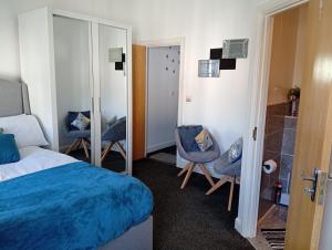 a bedroom with a bed and two chairs and a mirror at Precise Homes in Wolverhampton