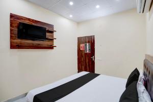 a bedroom with a bed and a tv on the wall at Hotel O Star Light in Rohtak