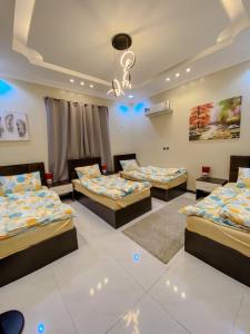 three beds in a room with blue lights at Abha Jacaranda in Abha