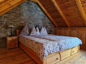 a bed in a room with a stone wall at Zora Vendégház in Tihany