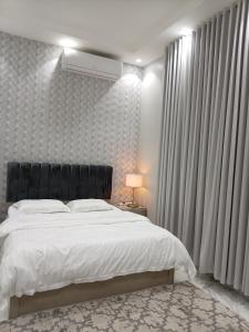 a bedroom with a large bed with a black headboard at شاليه ريف المملكة in Hail +3 photos