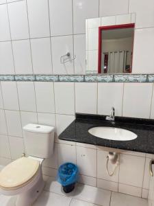 a bathroom with a toilet and a sink and a mirror at Pousada Marialva in Barreiras