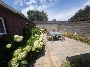 a patio with a table and chairs and flowers at B&B Chili Hoeve in Wanroij