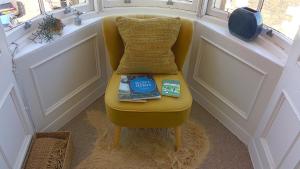 a yellow chair with books on it next to a window at Turret View - spacious central location in Peebles