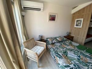 a bedroom with a bed and a chair and a window at Les OLIVETTES CLIMATISÉES d'UZES à Garrigues Sainte Eulalie in Garrigues-et-Sainte-Eulalie