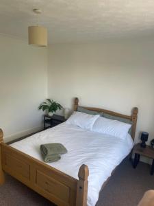 a bed with white sheets and a green towel on it at Penrhyn View in Bangor