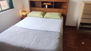 a bedroom with a white bed with a wooden headboard at Sobrado Jardim Itália in Itapetininga
