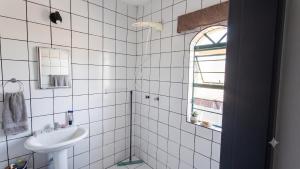 a white tiled bathroom with a sink and a mirror at Sobrado Jardim Itália in Itapetininga