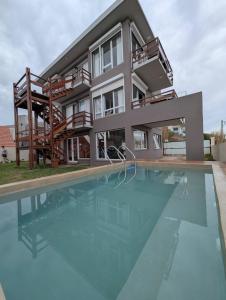 a house with a swimming pool in front of it at Cabañas Agreste in Villa Gesell