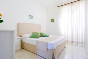 a white bedroom with a bed with two green pillows at Casa al Belvedere in Vico Equense