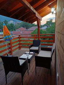 a deck with chairs and tables and an umbrella at Стаи за гости "Архангел Михаил" in Kostenets