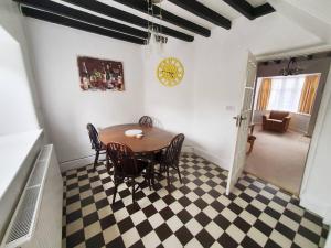 a dining room with a table and chairs on a checkered floor at Cosy Bala House in Bala +8 photos