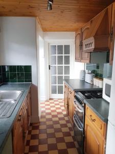 a kitchen with wooden cabinets and a checkered floor at Cosy Bala House in Bala