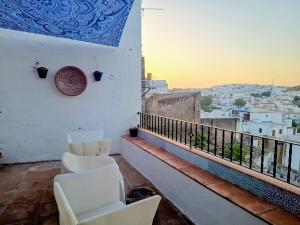 a balcony with white chairs and a view of a city at Ideal Perros Patio Privado Casa Jaruf in Arcos de la Frontera