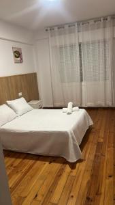 a bedroom with a white bed and a wooden floor at Hotel Termas Camino Real in Ourense