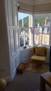 a living room with a chair and a large window at Turret View - spacious central location in Peebles