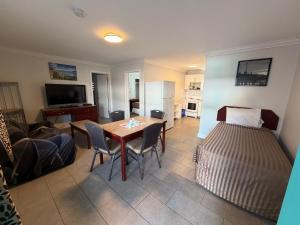 a living room with a table and a bed at Traveler's Motel Penticton in Penticton