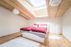 a bedroom with a bed with red sheets and a skylight at Tyrolhaus in Grinzens