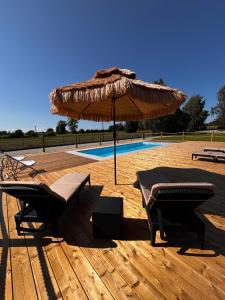a patio with a table and an umbrella and a pool at Z Nurtem Rzeki Domy z basenem Podlasie in Korycin