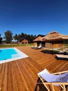 a wooden deck with a swimming pool and a hut at Z Nurtem Rzeki Domy z basenem Podlasie in Korycin