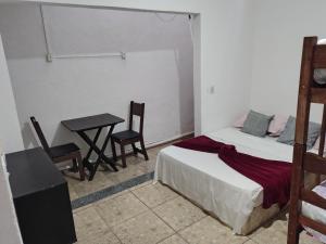 a bedroom with a bed and a table and a desk at Kitnet Centro in Capitólio