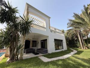 a white house with palm trees in the yard at Villa Anfa in Casablanca