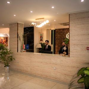 two men in a mirror at a salon at Consal Hotel 康赛尔酒店 in Baghdād