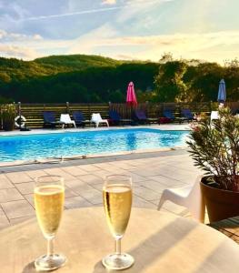 two glasses of wine sitting on a table next to a pool at Hôtel Les Gabarres in Tour-de-Faure +37 photos