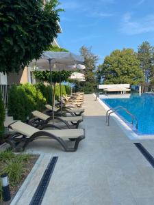 a row of chairs and umbrellas next to a swimming pool at Open Sea Panorama Residence in Obzor