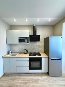 a kitchen with white cabinets and a refrigerator at Apartment Versailles Park 1 in Irpin +11 photos