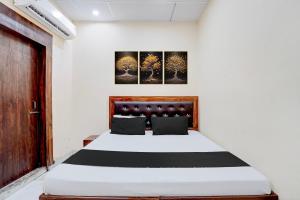 a bedroom with a white bed with a wooden headboard at Hotel O Star Light in Rohtak +26 photos