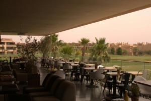a restaurant with tables and chairs and a field at Prestigia Golf City Apartment in Marrakesh