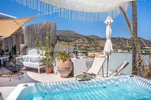 a patio with a hot tub and chairs and an umbrella at Malia Boutique Studios in Malia