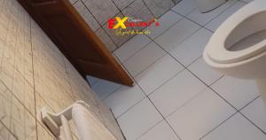 a bathroom with a toilet and a white tile floor at Appart meublé Excellentia Edea in Edéa +21 photos