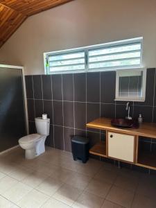 a bathroom with a toilet and a desk with a computer at Studio indépendant in Otutara