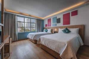 ein Hotelzimmer mit zwei Betten und einem Fernseher in der Unterkunft Hotel More By Kavia in Mexiko-Stadt