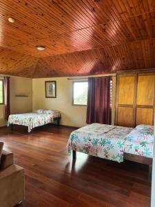 a bedroom with two beds and a wooden ceiling at Studio indépendant in Otutara