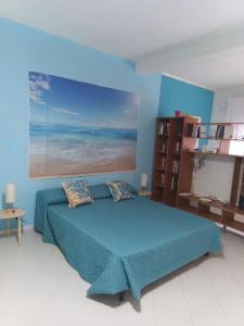 a blue bedroom with a bed and a painting on the wall at Green House in Briatico