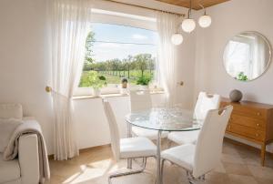 a dining room with a glass table and white chairs at Idyllische Wohnung mit Weitblick in Neukirchen-Vluyn